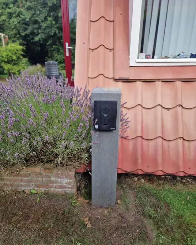 Laadpaal op een stenen zuil in de voortuin