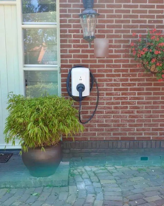 Laadpaal aan een rode bakstenen gevel naast de voordeur