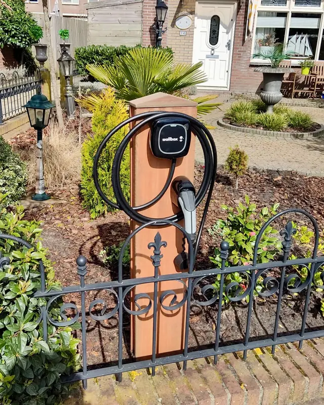 Laadpaal op een paal in een voortuin