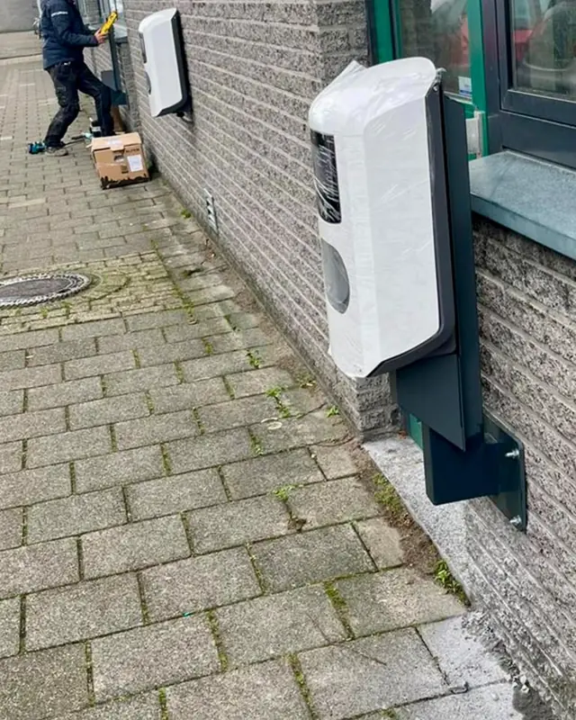 Monteur aan het werk bij een laadpaal aan de gevel