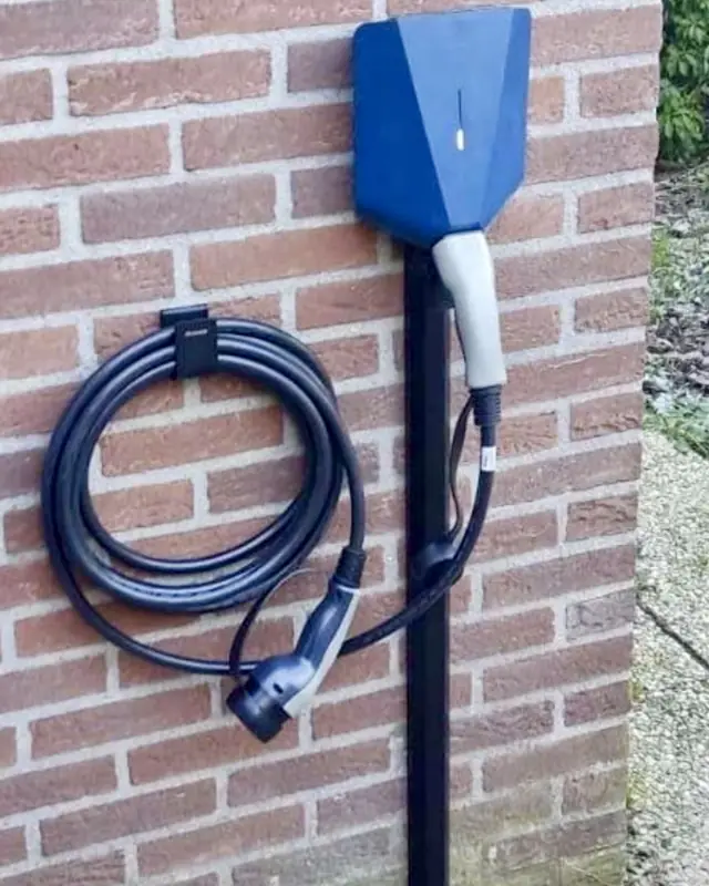 Laadpaal met blauwe cover aan een bakstenen muur