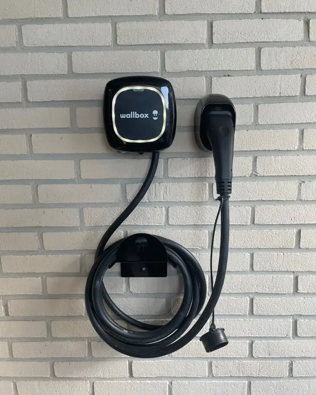Wallbox-laadpaal met kabelhouder aan een witte gevel