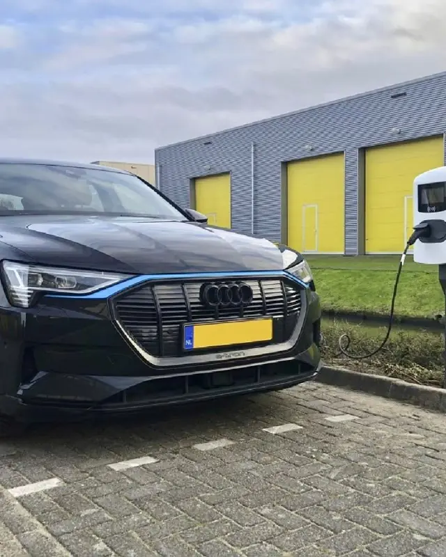 Zakelijke laadpaal bij een bedrijfshal, met een ladende auto