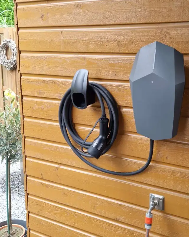 Laadpaal met kabelhouder op een houten schuur
