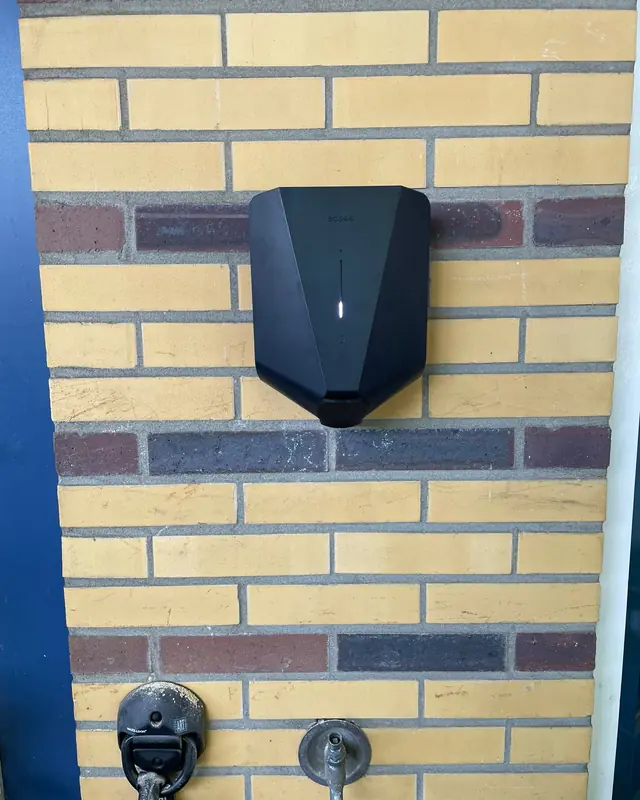 Laadpaal aan een gele bakstenen gevel