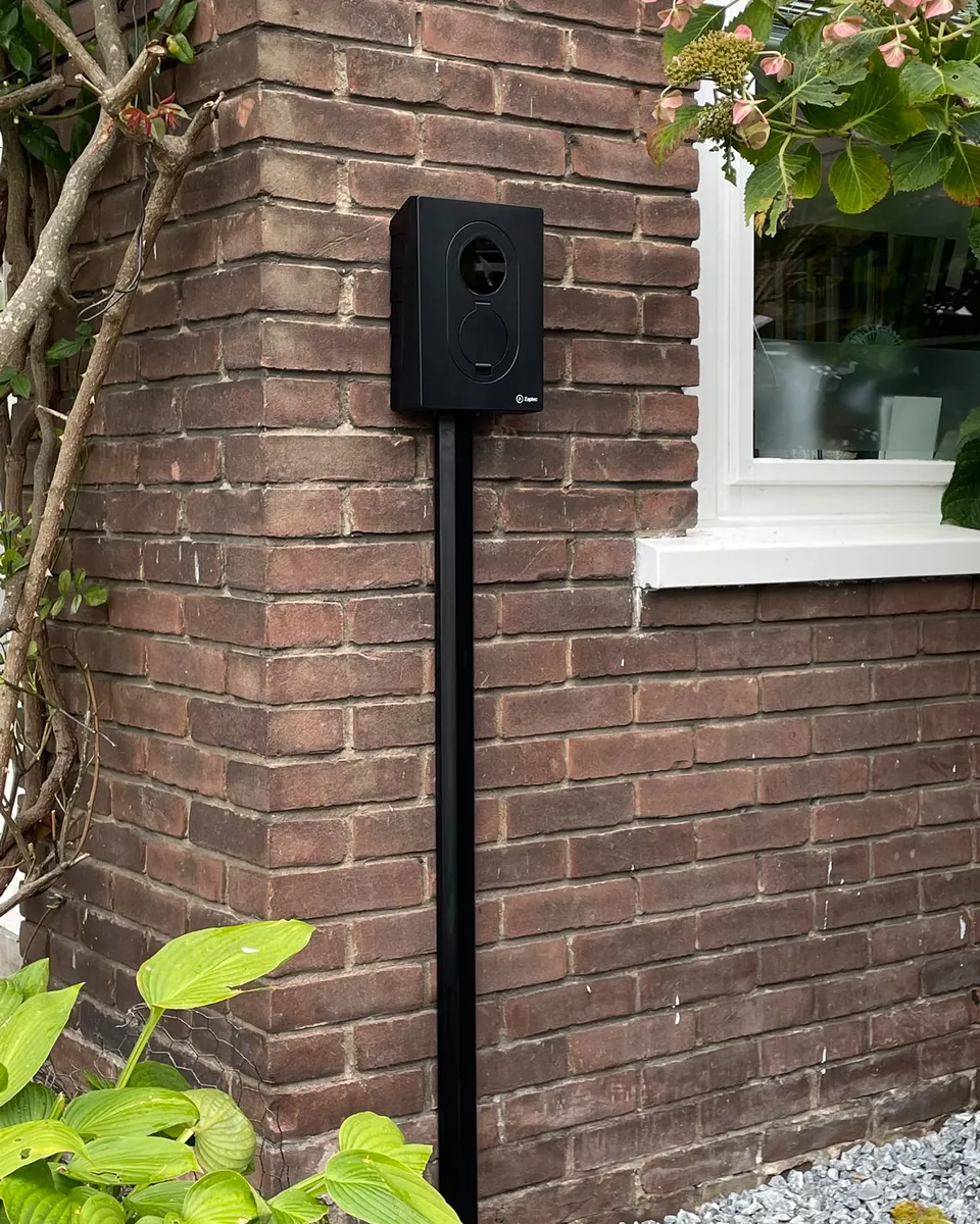Zaptec Go 2 aan de gevel, met de kabel weggewerkt in een zwarte aluminium kabelgoot