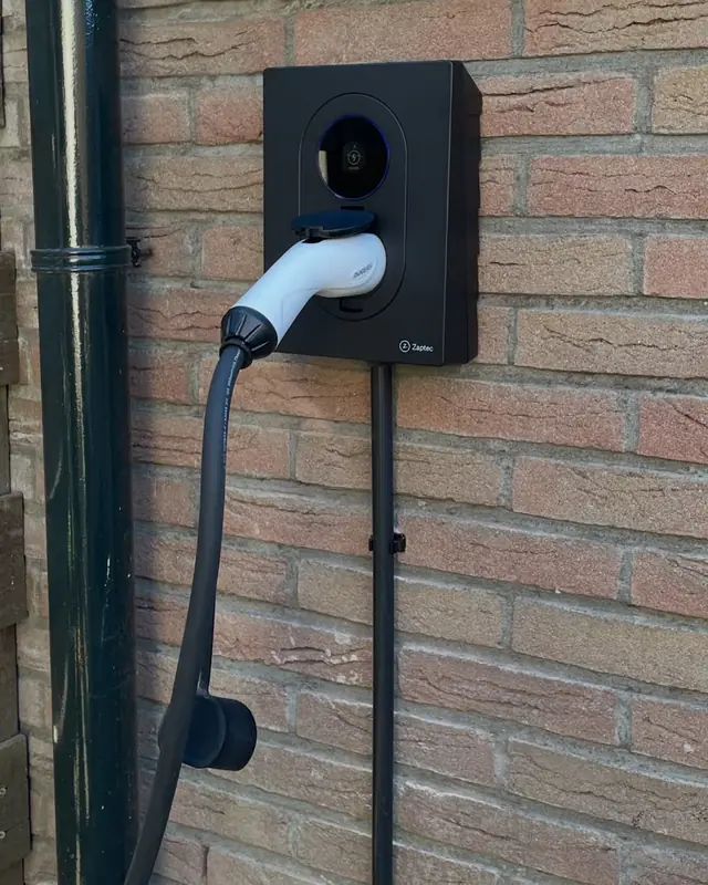 Laadpaal met kabel aan een bakstenen gevel